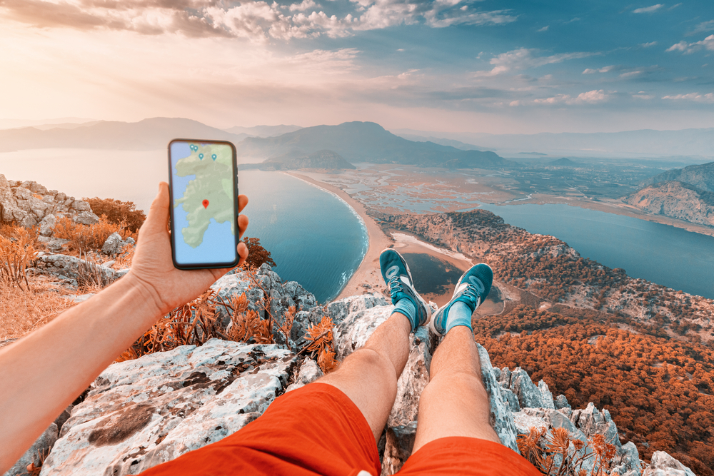 turista s telefonom v ruke na vrchole hory