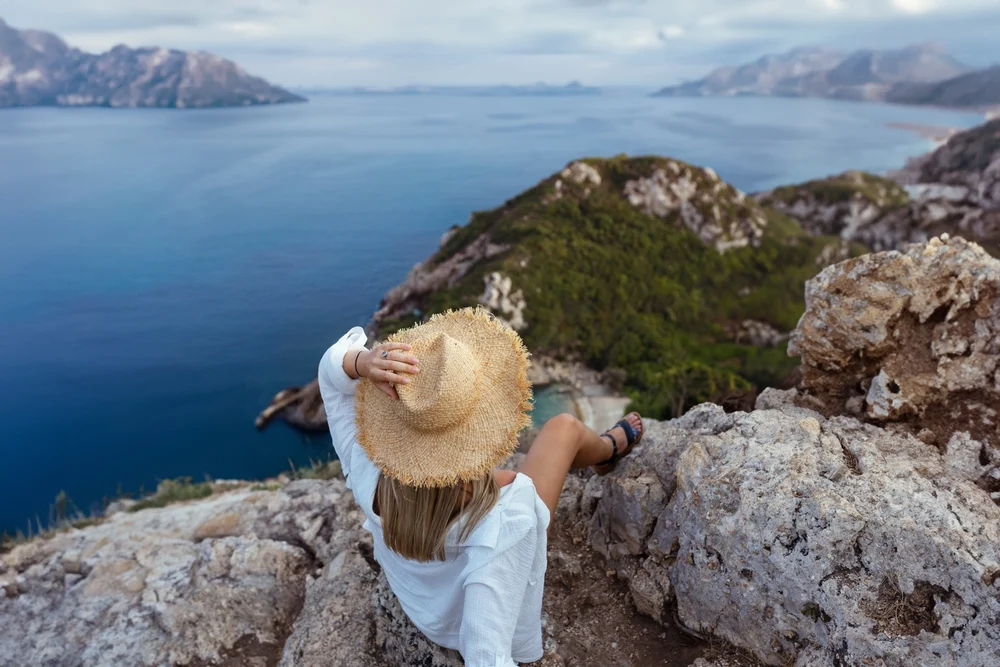 turistka sediaca na skale na korfu
